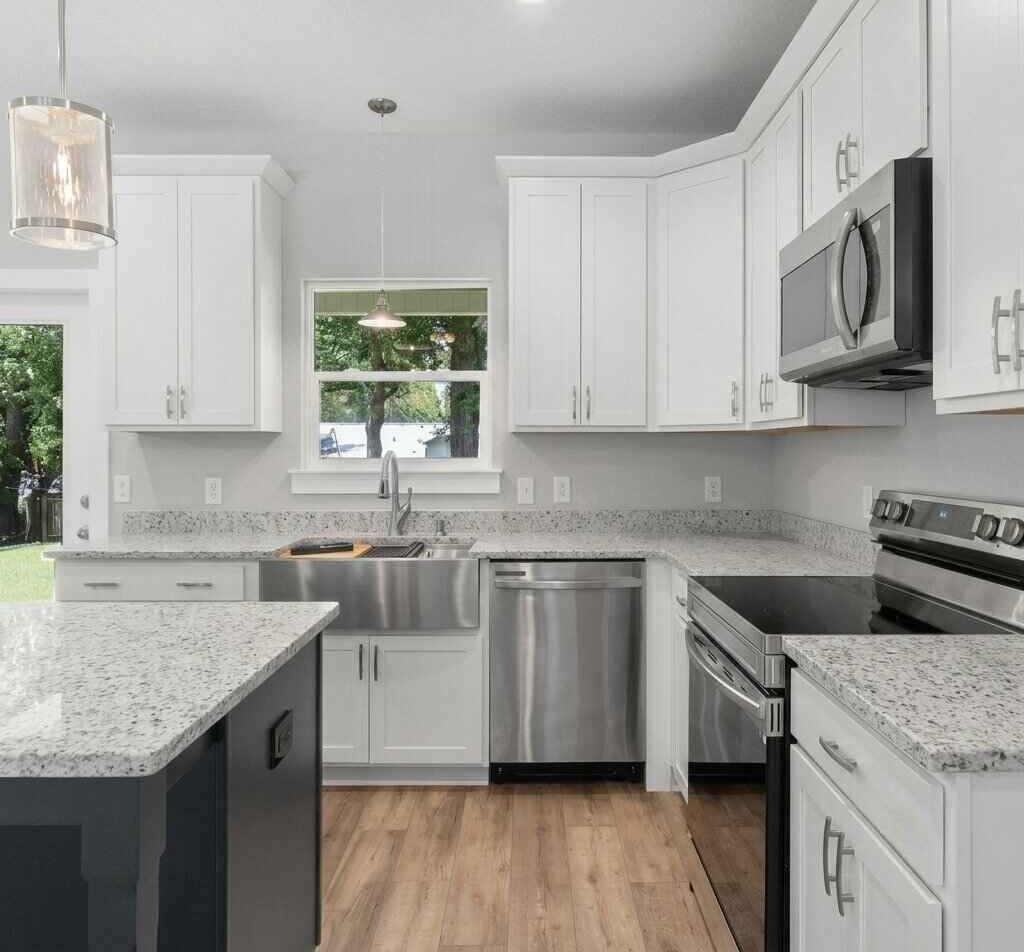 Modern kitchen with white cabinets, granite countertops, stainless steel appliances, and a dark island